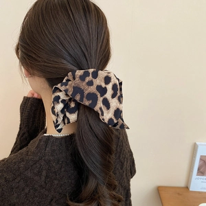 Détail du chouchou en satin à motif léopard avec nœud élégant dans une queue