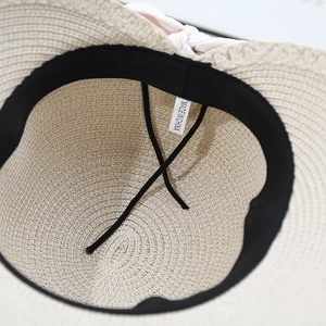 Straw sun hat with pink ribbon bow and detailed openwork weave for summer beach wear