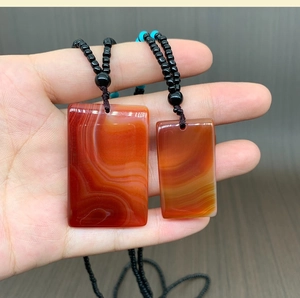 Detailed comparison of large and small red agate pendant plaques with silk textures