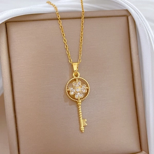 Macro shot of gold key pendant necklace featuring a clover shape with sparkling zircons