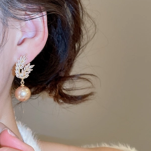 Close-up of elegant gold leaf earrings with champagne pearls and shimmering crystals