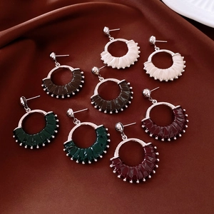Detail shot of fan-shaped leather earrings in four colors on silk fabric background