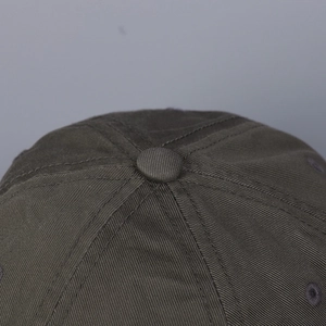 Dettaglio ravvicinato di un berretto in cotone verde oliva con bottone e trama twill