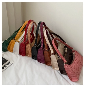 Detail view of colorful crocodile-embossed underarm bags in eleven stylish color options