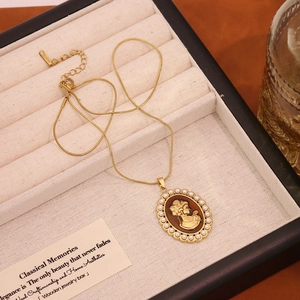 Macro shot of gold stainless steel necklace with pearl cameo pendant in a velvet box