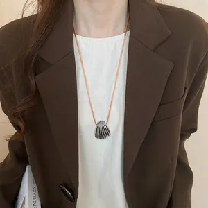 Silver shell pendant necklace with a light brown woven cord on professional model outfit