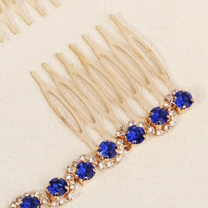 Detailed close-up of golden bridal hair comb with blue crystals and sparkling rhinestones