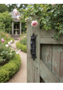 Detail of vintage black cast iron door handle with ornate European carvings on rustic wood