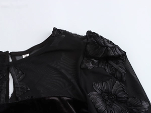 Detail of black velvet dress featuring delicate 3D floral embroidery and mesh paneling