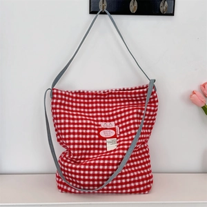 Close-up of red and white plaid tote bag with grey straps and decorative brand label