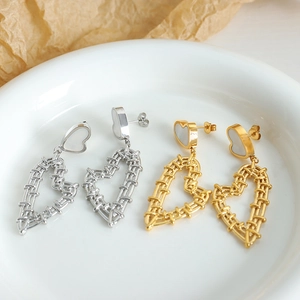 French style gold and silver woven heart drop earrings on a minimalist ceramic plate