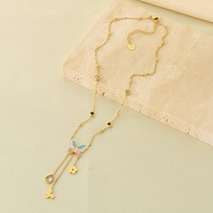 Macro view of gold butterfly pendant with gradient wings and drop zircon on steel chain