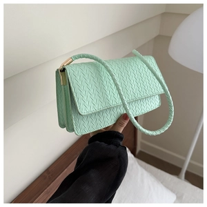 Close-up of mint green woven texture crossbody bag with gold metallic lock detail