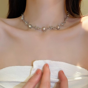 Detail view of a silver thorn-style necklace with a round opal pendant on a model