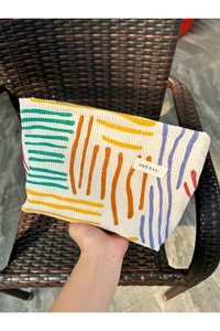 Detailed close-up of corduroy makeup bag with abstract art lines and metal zipper