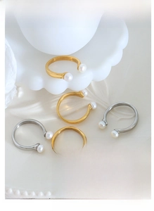 Detail of baroque freshwater pearl gold and silver U-shaped open rings on a ceramic plate