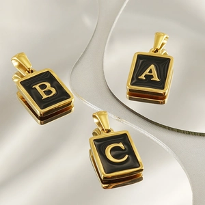 Macro shot of 18K gold plated rectangular pendants with black enamel and letters A, B, C