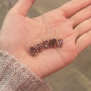 Dettaglio di unghie finte cat-eye rosa e marroni con glitter e decorazioni a cuore