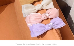 Detail of four colorful satin bow headbands in gold, white, pink and purple on a soft fabric