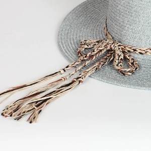 Detail of light blue straw sun hat showing intricate weave and tassel cord trim