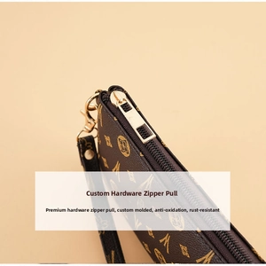 Detailed close-up of golden metal zipper and brown monogram pattern on a vintage clutch