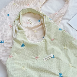 Detail of embroidered bow patterns on textured seersucker canvas shoulder bag