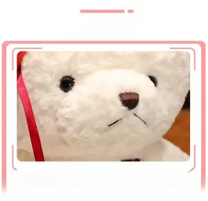 Close-up of white plush teddy bear showing detailed faux fur texture and red satin ribbon