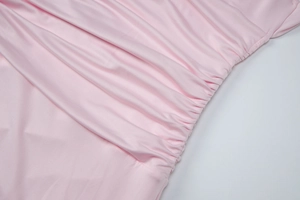 Detailed view of pink ruched fabric with smooth texture and elastic draped design