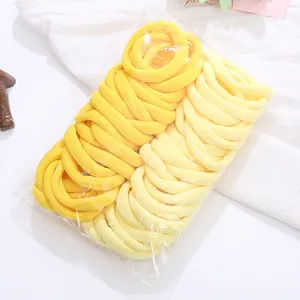 Close-up of bright and cream yellow high-elastic towel cloth hair ties in bulk packaging