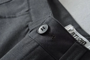 Makro-Detail der High-Waist-Hose mit Knopfverschluss und strukturierter Stoffoberfläche
