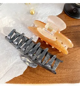 Detail of marble pattern and amber acrylic hair claws on a wooden surface backdrop