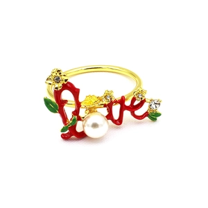 Gold metal napkin ring detail featuring red Love letter design, pearl and rhinestones.