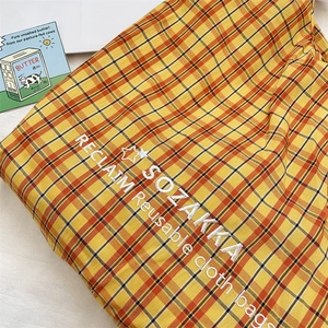 Close-up of orange plaid canvas tote bag showing detailed embroidery and texture
