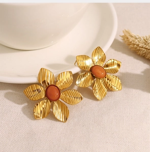 Detail of French vintage gold flower earrings with natural orange stone center