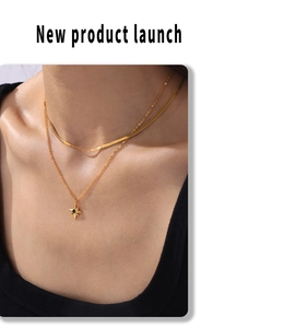 Detail of layered gold star pendant necklace and sleek snake chain on a female model