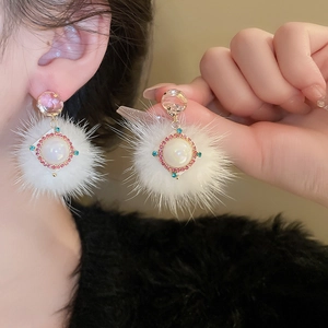 Detail of white pom-pom earring with crystal studs, pearls and rhinestones on ear