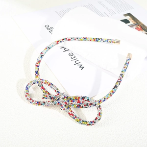 Close-up of colorful rhinestone bow headband with glittering crystals and gold tips