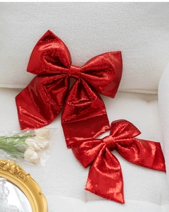 Close-up of red sequined Christmas bows on soft white fleece with decorative golden frame