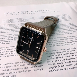 Close-up of square quartz watch with black dial and brown leather strap on newspaper