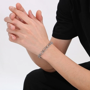 Close-up of a silver stainless steel curb chain bracelet worn on a model's wrist