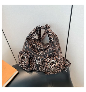 Detailed view of leopard print backpack with multiple zippered pockets and silver rings