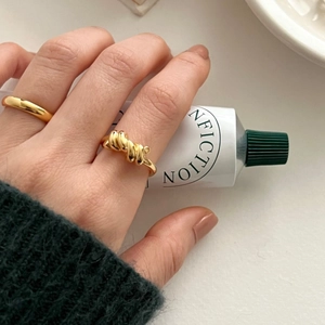 Detail of gold knot ring and matching band stacked on finger for an elegant minimalist look