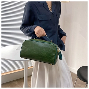 Détail d'une trousse de toilette en cuir PU vert foncé avec une grande poignée de transport