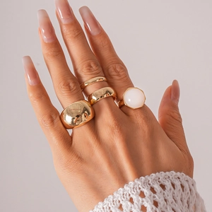 Close-up of a 4-piece gold metal and resin ring set worn by a model in a stacked style