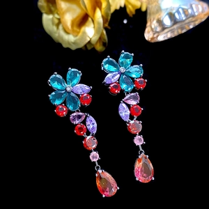Detailed close-up of long floral earrings with colorful gemstones and teardrop tassels