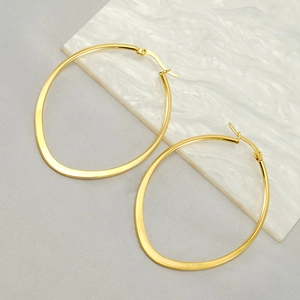 Detailed view of oval 18k gold plated stainless steel hoops on marble background