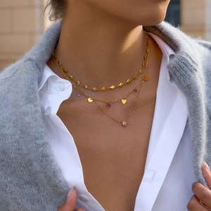 Détail du collier multicouche doré 18k avec breloques cœurs et zircons roses et violets