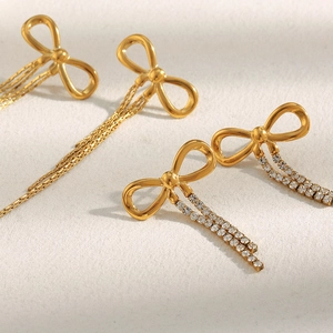 18K gold plated stainless steel bow earrings with zircon tassels on textured surface