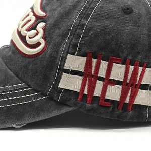 Detail of red 3D embroidery and white stitching on vintage washed cotton baseball cap