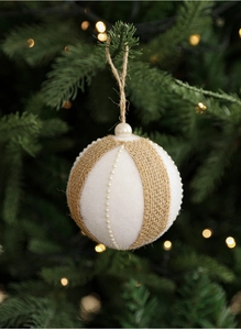Detail of burlap and velvet Christmas ball with faux pearl trim hanging on a tree branch